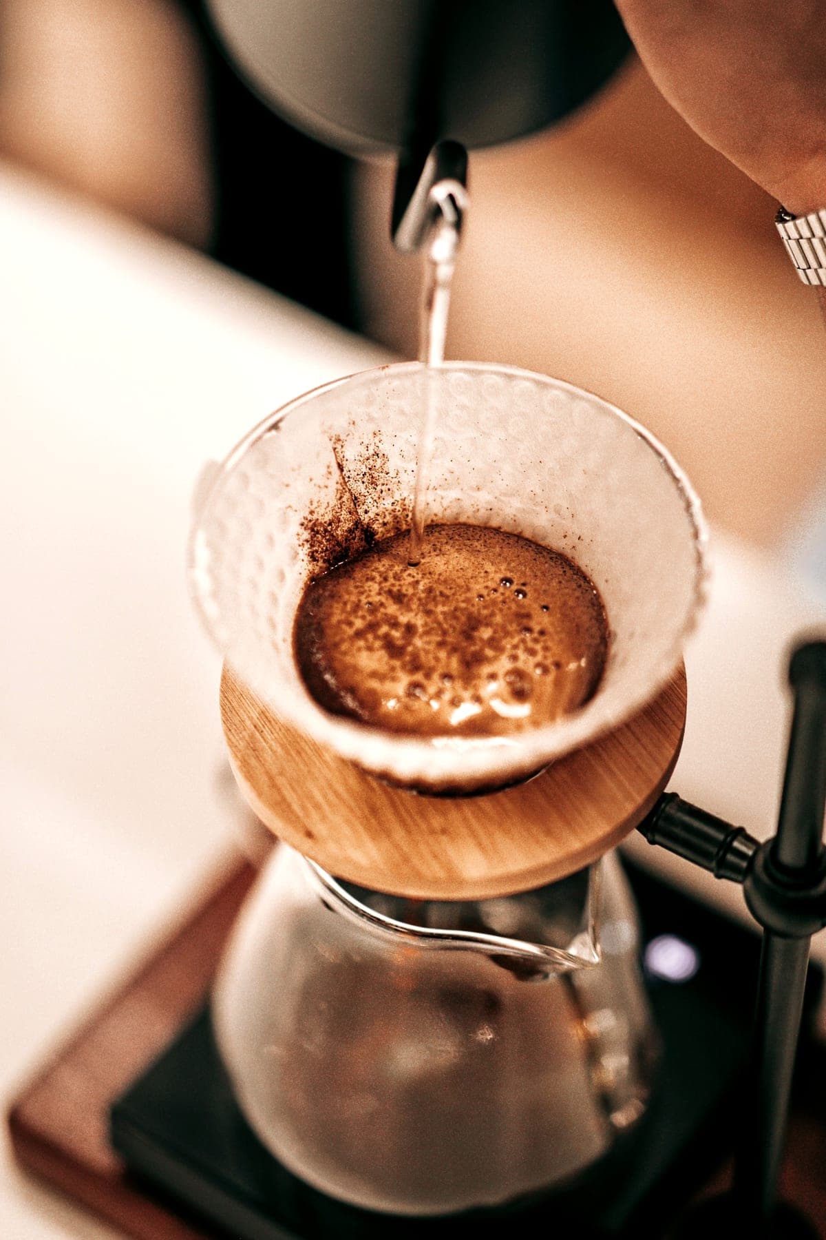 Water poured from a gooseneck kettle onto coffee in a pour-over dripper.