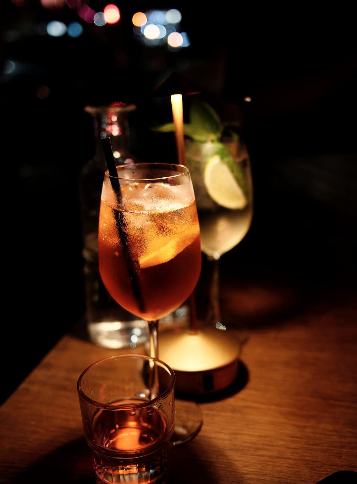 Two cocktails and a candle on a wooden bar table in the evening.
