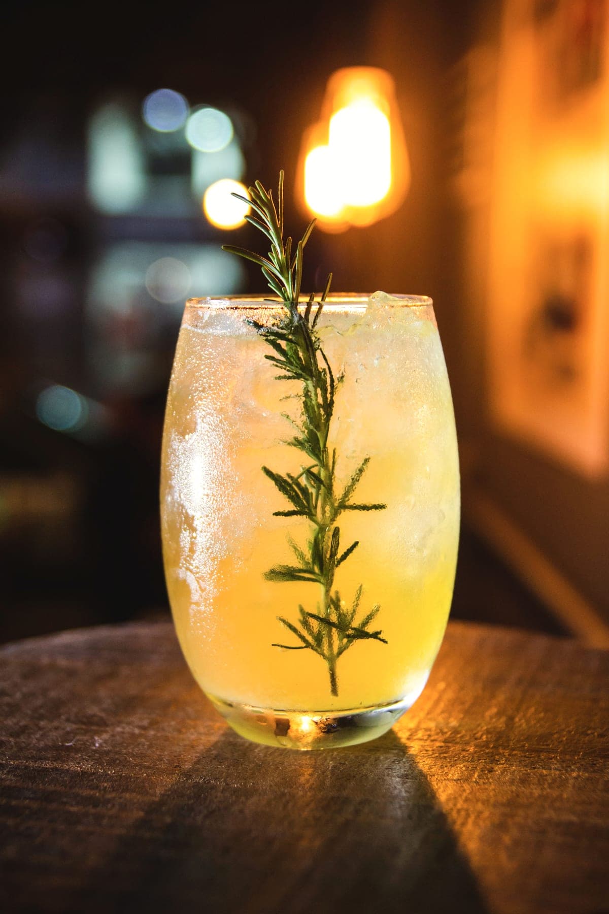 The alcohol-free Garden Spritz over ice, with a sprig of rosemary, in warm evening light.