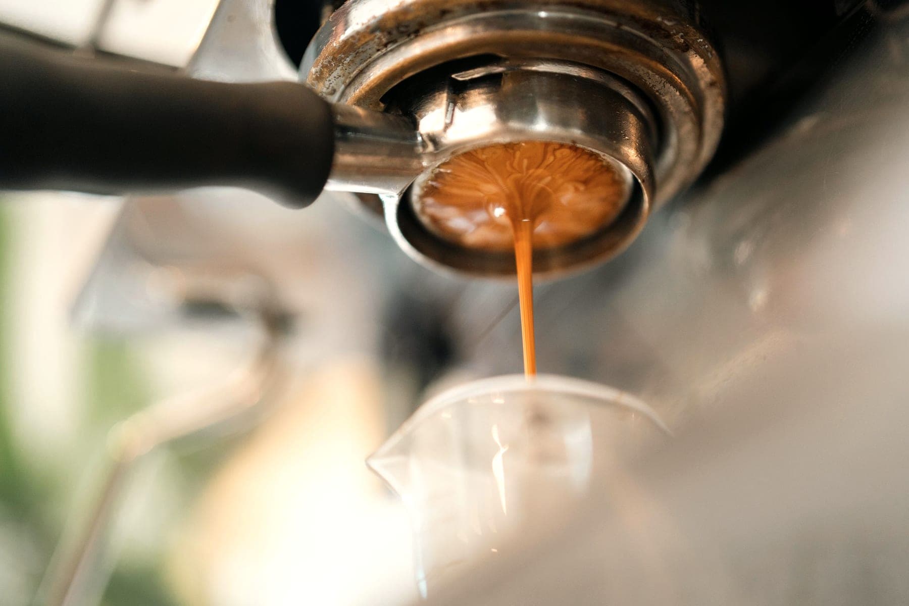 A close-up of espresso running from the portafilter into a glass.